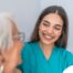 A caregiver smiles with an older client showing the results of successfully starting a new caregiving job.