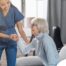 A caregiver demonstrates her caregiver skills by helping an older adult get up.