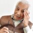 An older adult holds his head and his glasses representing vision problems like macular degeneration.