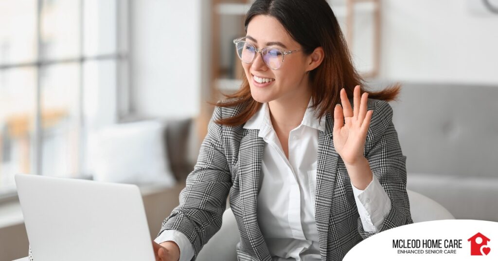 A well-dressed woman smiles and says hi on a videoconference, representing a candidate who is well-prepared for a caregiver interview.
