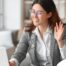 A well-dressed woman smiles and says hi on a videoconference, representing a candidate who is well-prepared for a caregiver interview.