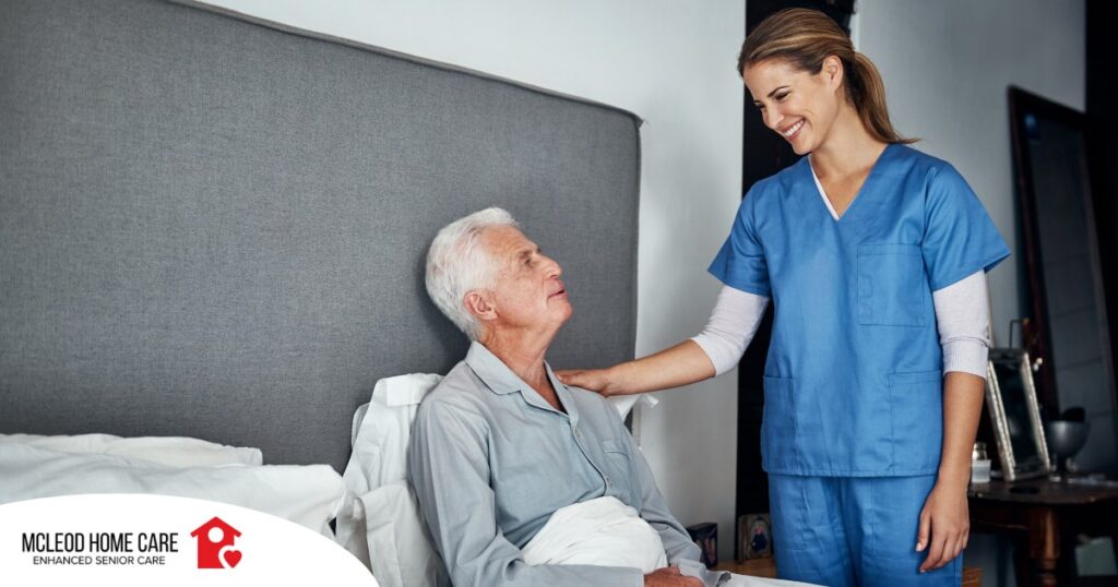 A caregiver smiles at an older client in bed, representing the compassion involved in being a live-in caregiver.