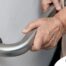An older adult uses a grab bar representing one of the home modifications that is helpful for fall prevention for elderly adults.