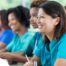 Several students in scrubs happily attend a class, representing caregiver training.
