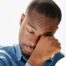 A man tiredly rubs his eyes, representing the exhaustion that can come with family caregiving.