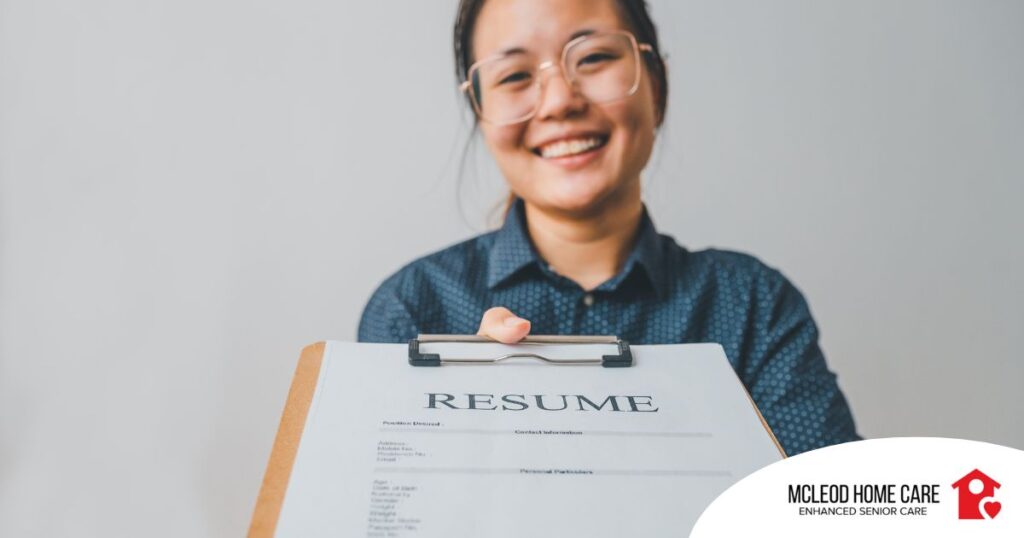 A woman happily hands in a resume, representing a successfully written caregiver resume.
