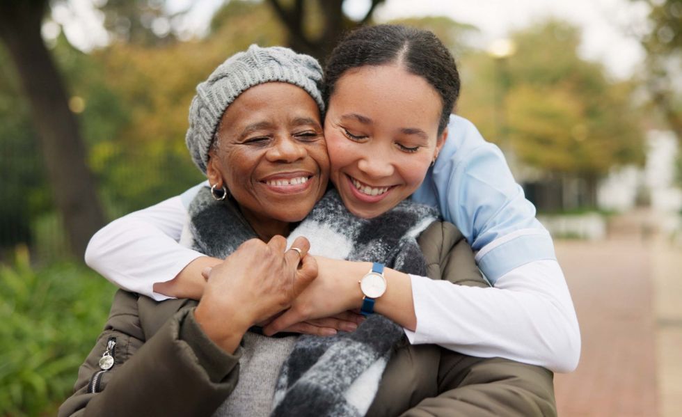 Alzheimer’s & Dementia Care in Charleston Caregiver embracing a senior woman outdoors, reflecting compassionate Alzheimer’s & Dementia Care in Charleston